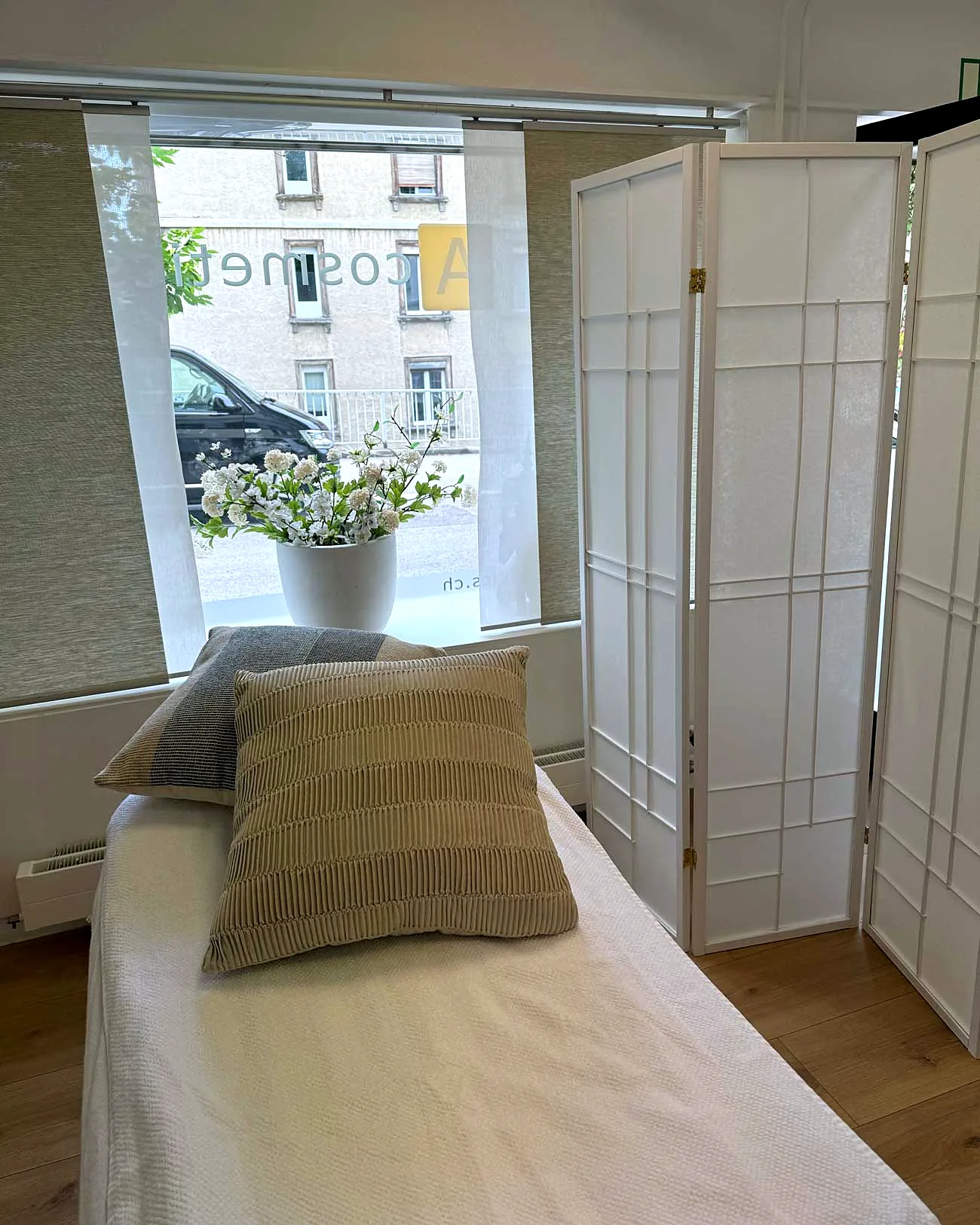Behandlungsliege mit Kissen vor dem Fenster