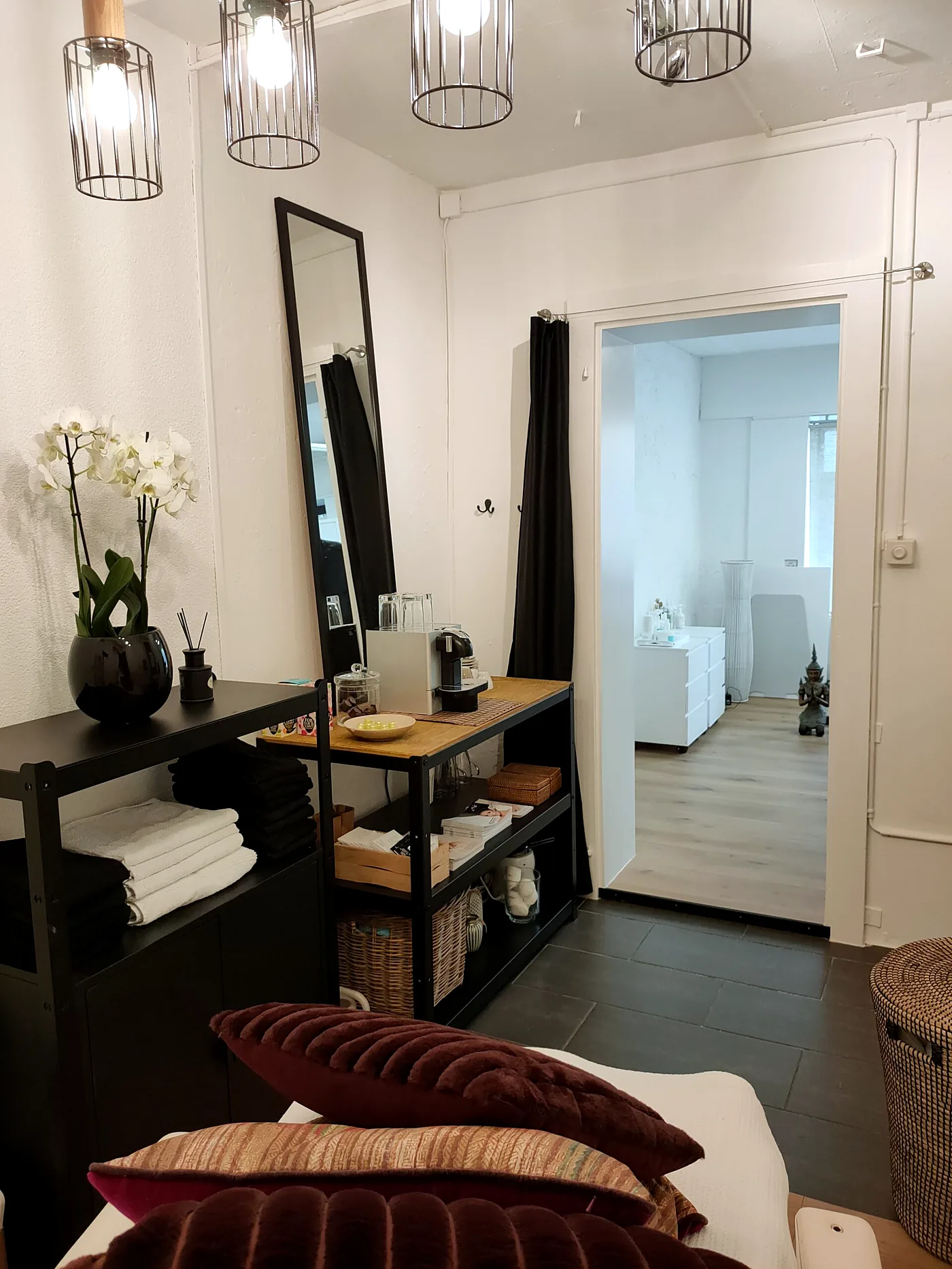 Behandlungsraum mit Orchidee, Spiegel und Blick in den Nebenraum